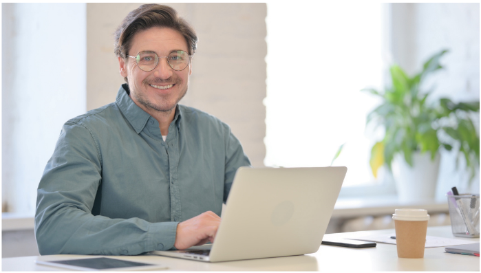 man on laptop smiling at camera